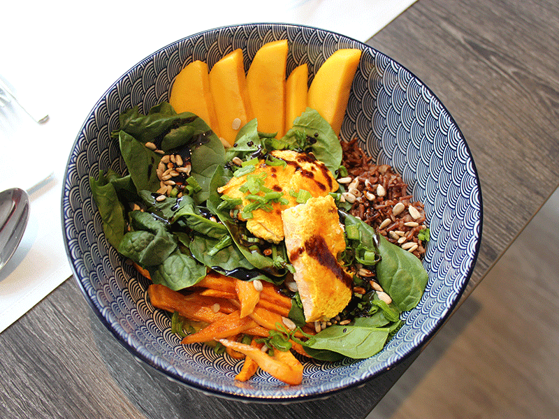Schüssel mit Mango, Salat, Sprossen und Körnern